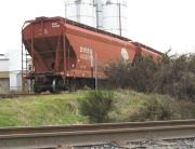Two covered hopper freight cars on embankment and in front of solos