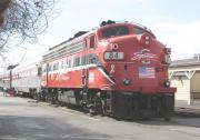Red locomotive and several silver colored passenger cars